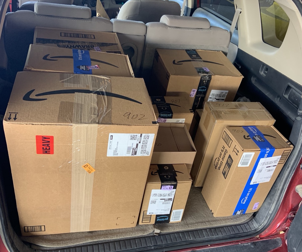 The cargo area of a red SUV loaded with Amazon packages for a delivery block