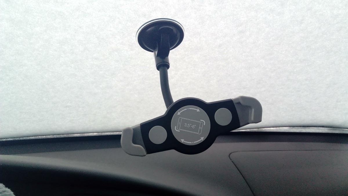 An empty smartphone holder clamped to a car windshield above the dashboard