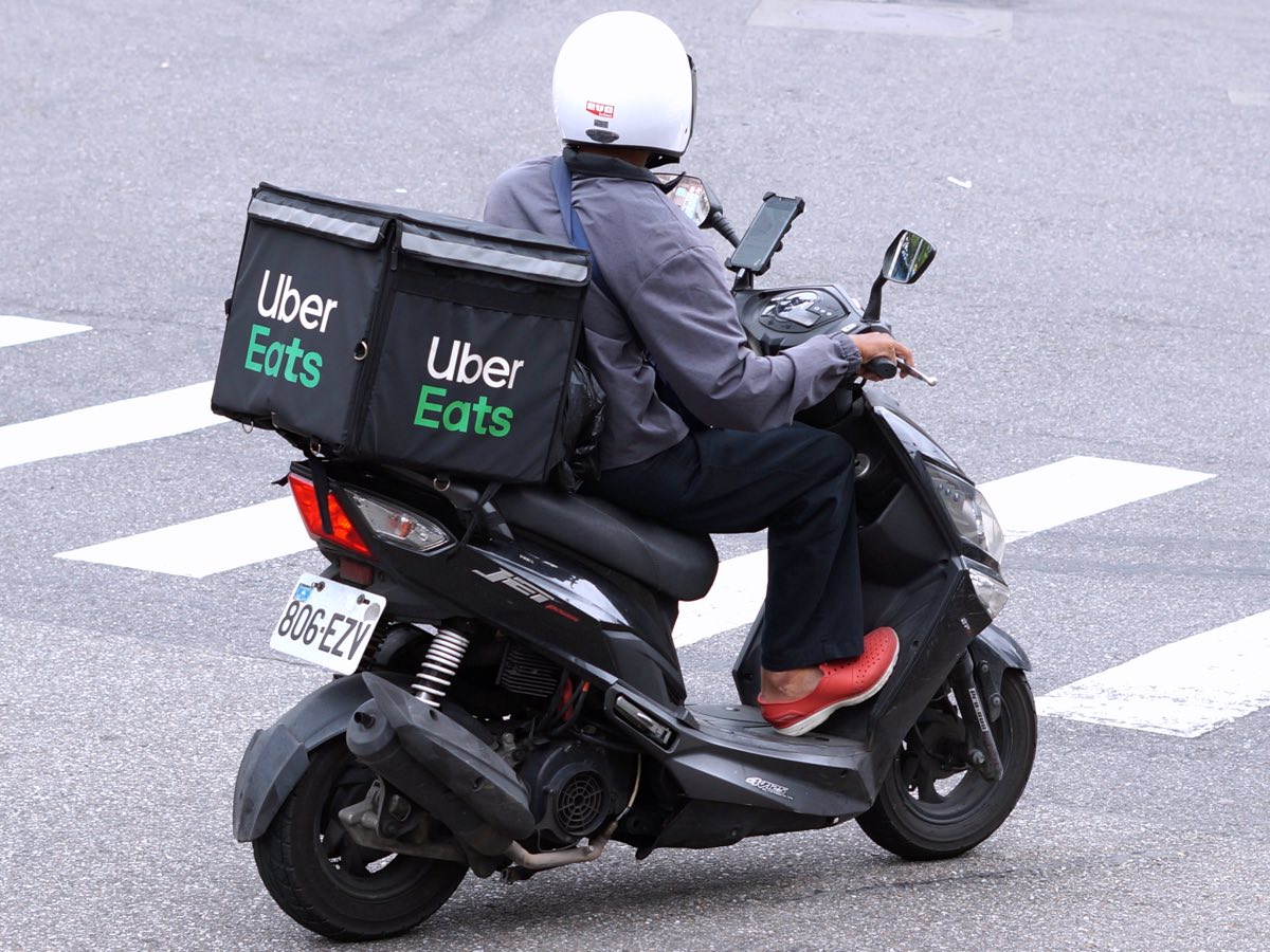 Figure 1.1: An Uber Eats courier on a scooter with an insulated delivery box and a phone mounted on the handlebar.